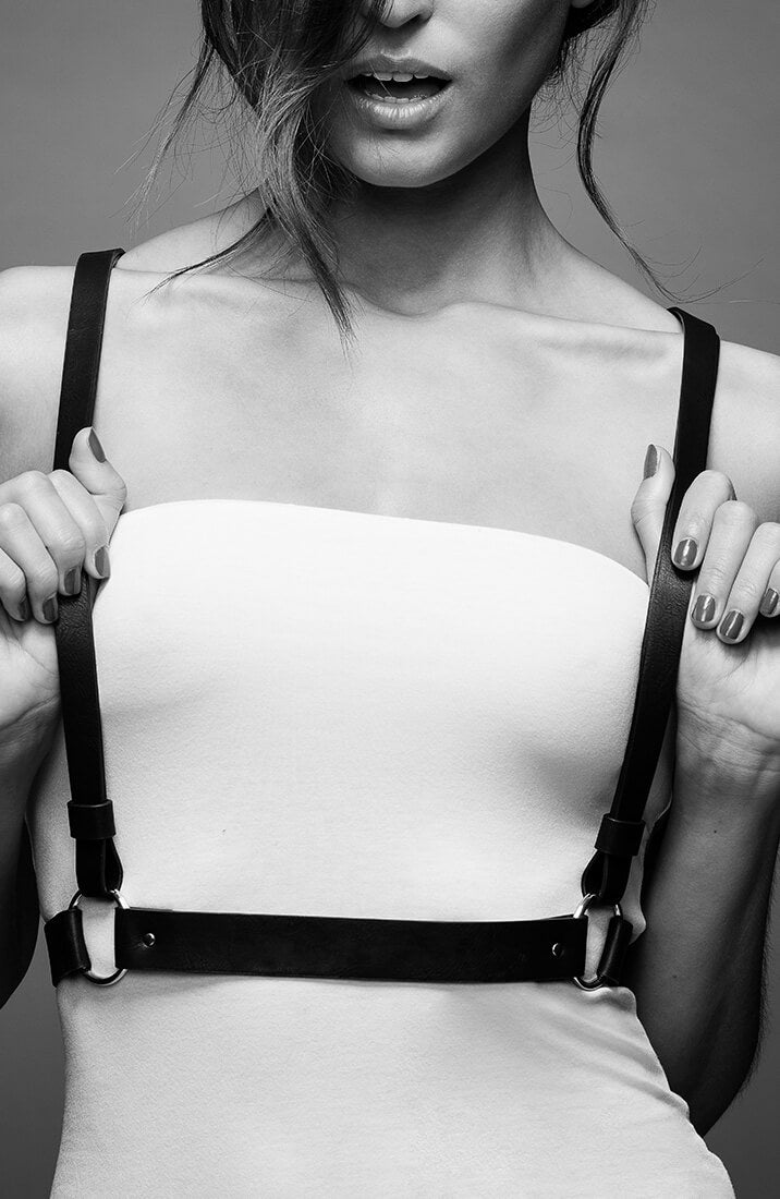 Model wearing faux leather body harness styled for erotic impact