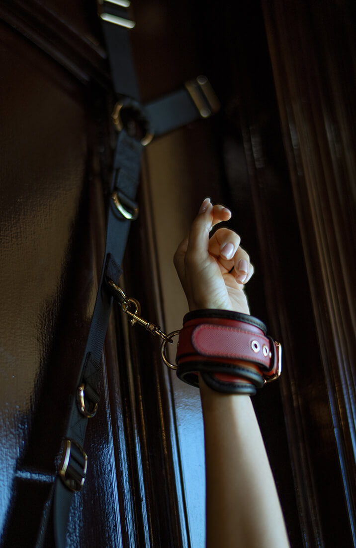 Close-up of burgundy padded wrist cuff attached to adjustable door restraint system